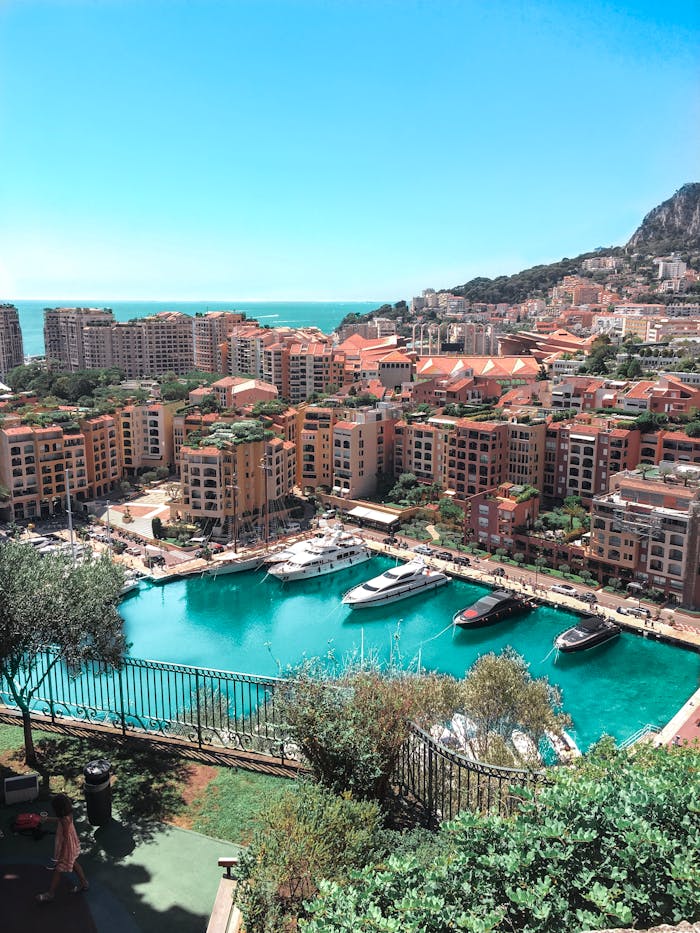 A stunning aerial view of Monte Carlo's vibrant harbor and surrounding cityscape under a clear blue sky.