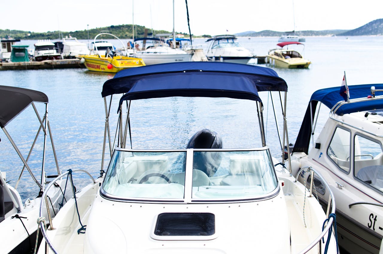 A serene marina scene featuring multiple boats docked on calm waters under a blue sky.