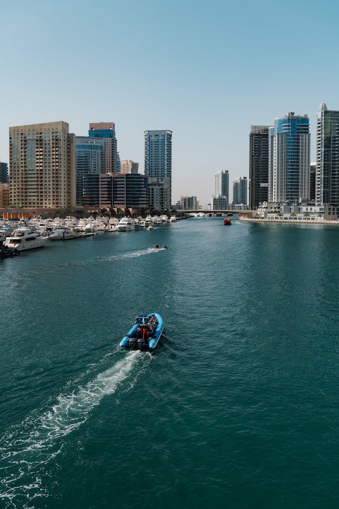 Scenic view of Dubai Marina with boats and skyscrapers under a clear blue sky.