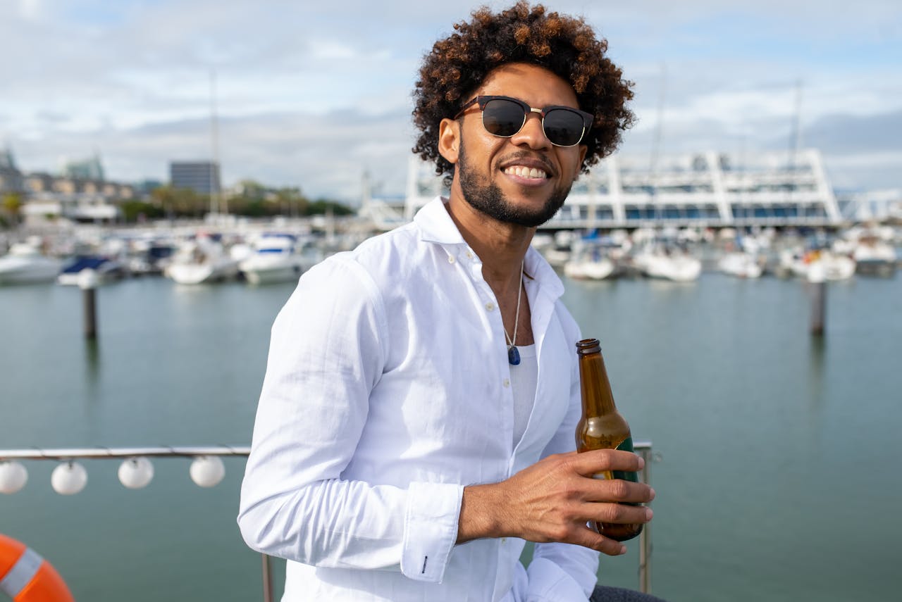 Smiling man enjoying a drink by the marina in Portugal, a perfect day for relaxation.