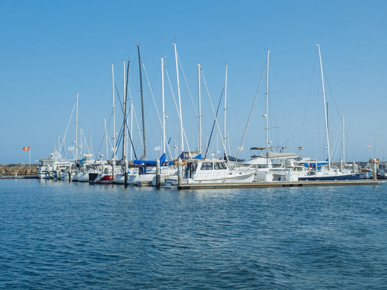 Scenic view of luxury yachts docked at Santa Barbara Harbor on a clear day.